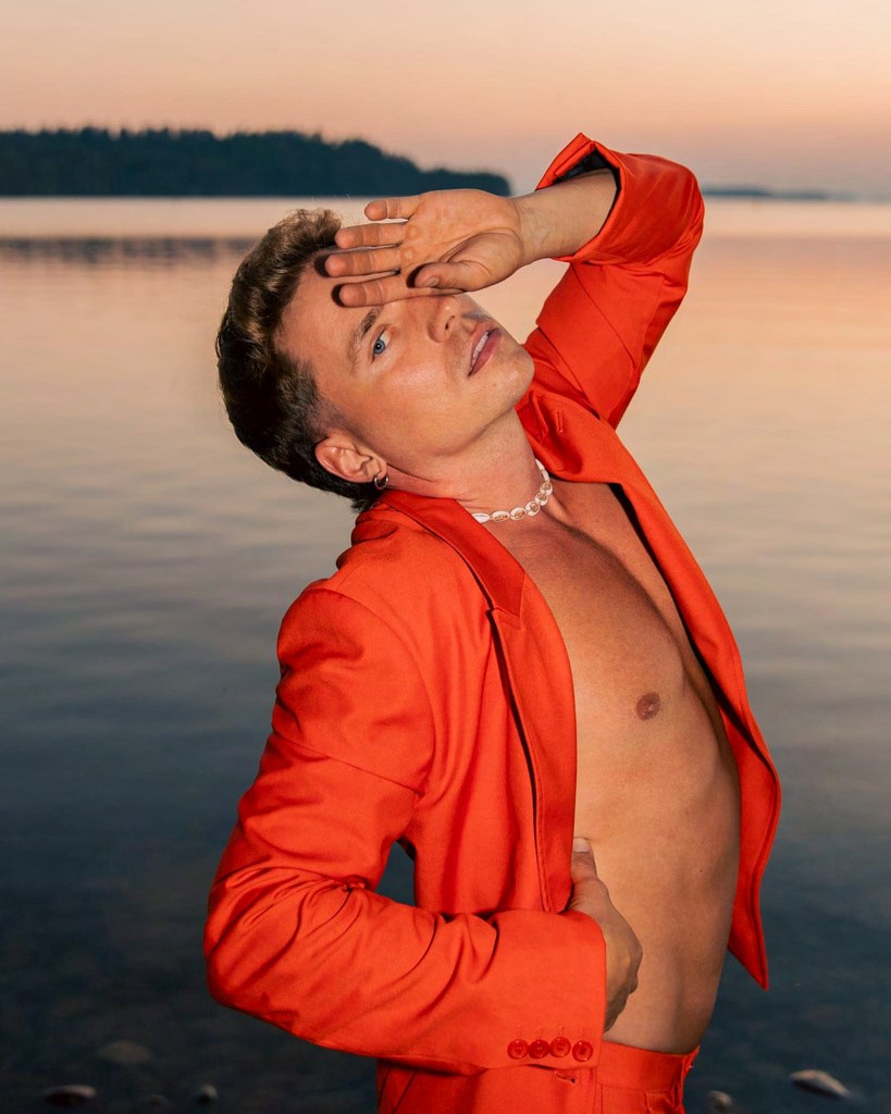 Toni in an orange outfit at sunset by the water
